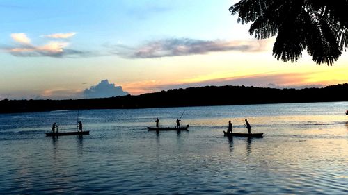 Silhouette boats in lake against sky during sunset