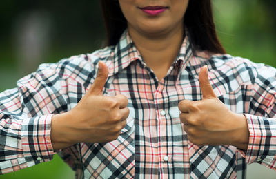 Midsection of smiling woman showing thumbs up 