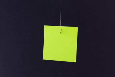 Close-up of yellow paper hanging against black background