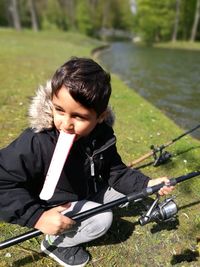 Full length of boy fishing while having ice cream by river