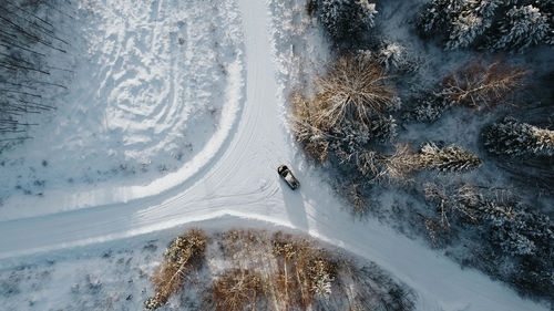 Aerial view of forest in winter mountain. three to four roads with car in the middle. estonia. 