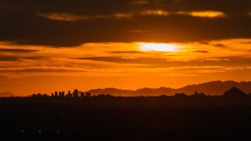 Silhouette landscape against dramatic sky during sunset