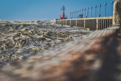 View of sea waves crashing at pier against sky