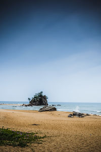 Rock formations at beach against blue sky