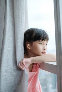 Cute baby girl looking through window