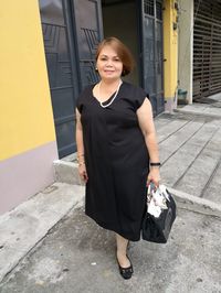 Portrait of woman standing on footpath in city