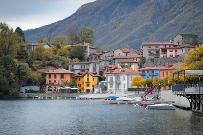 Buildings by river against mountain