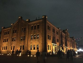 People on street against illuminated buildings in city at night