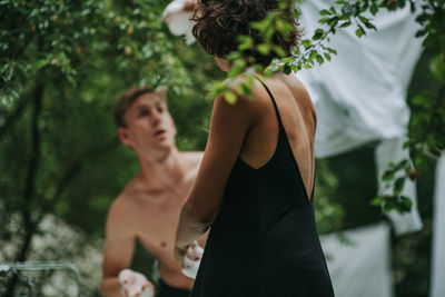 Midsection of couple standing against trees