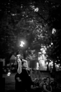 Rear view of people holding illuminated tree at night