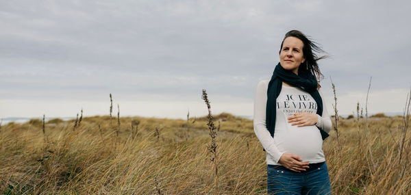 Pregnant woman standing on field against sky