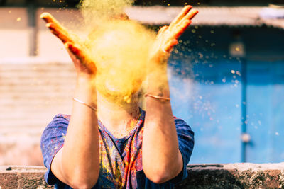 Young woman playing with powder paint during holi