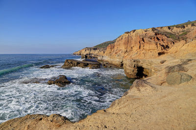 Rock formations on beach against clear sky