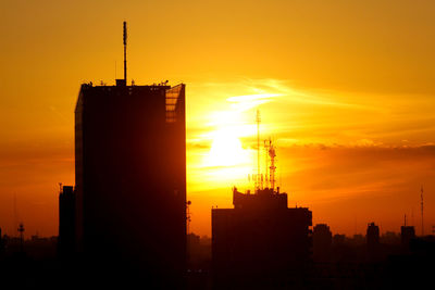 Silhouette built structure against orange sky