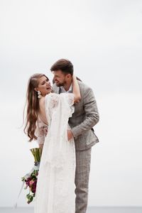 Bride and bridegroom standing against clear sky