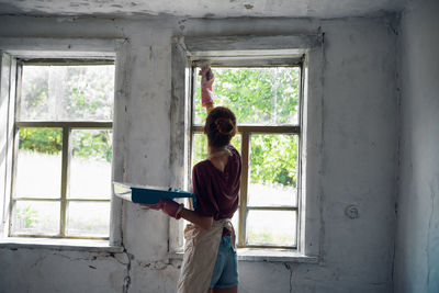 Rear view of woman looking through window