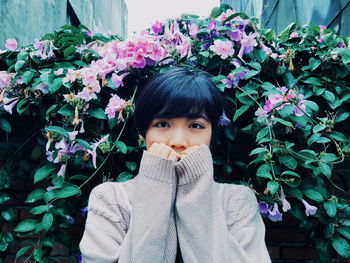 Portrait of woman standing against flowers