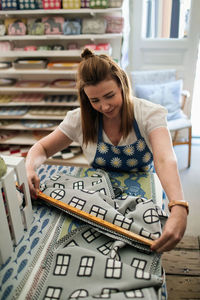 High angle view of owner measuring patterned fabric while working in shop