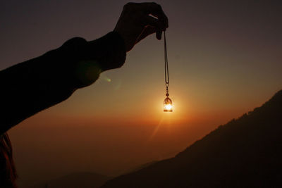 Silhouette person holding sun during sunset