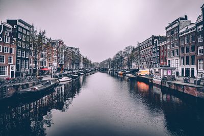 Canal amidst buildings against sky in city