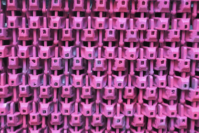 A collection of pink painted parts of a scaffoling construction