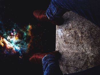 Low section of man standing on rock at night