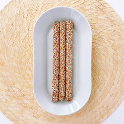 Plate with sesame breadsticks on place mat top view