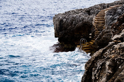 Rock formation and steps with ladder on sea shore