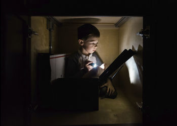 Boy hiding in cabinet and reading at home