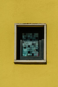 Close-up of window on yellow wall