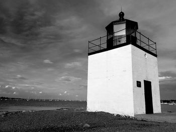 Low angle view of lighthouse by lake against cloudy sky