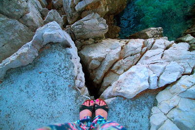 Low section of woman standing on rock by sea