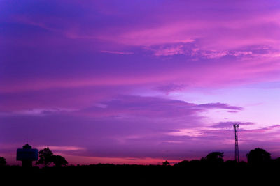 Silhouette of trees against dramatic sky at sunset