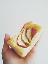 Close-up of hand holding food over white background