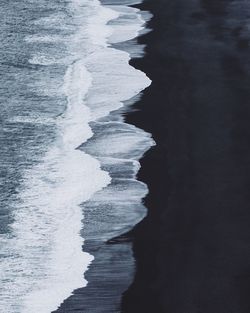 Sea waves crashing on black sand beach in iceland