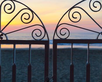 Close-up of railing against sea during sunset