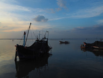 Fishing boat moored on sea against sky