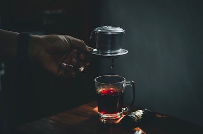 Midsection of man holding wine glass on table