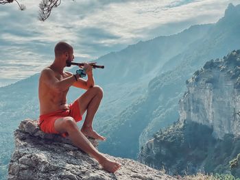 Side view of woman sitting on rock