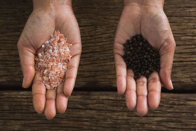 Close-up of hands holding sea salt and black pepper seeds