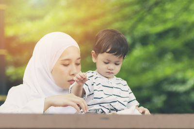 Mother and son holding piggy bank on table