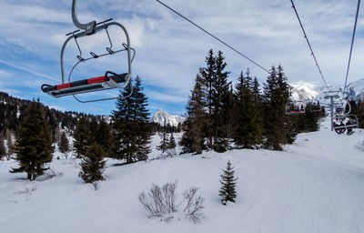 Ski lift over snow covered mountains against sky