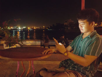 Side view of young man using mobile phone at table