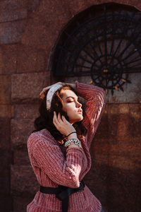 Young woman standing against building