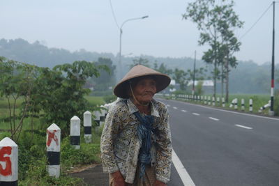Woman standing by road against sky