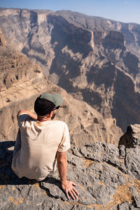 Rear view of man sitting on rock