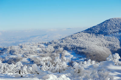 Scenic view of snow covered mountains against blue sky