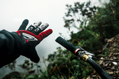 Cropped image of mountain biker wearing glove against trees