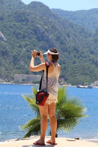 Young woman standing by tree against mountain