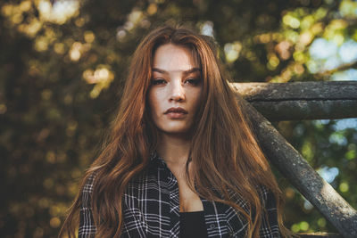 Portrait of young woman standing against tree